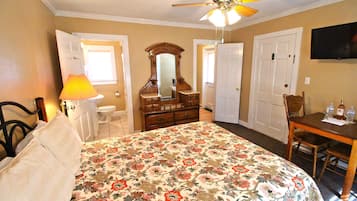 A bedroom with a bed, dresser, mirror, and a TV on the wall.
