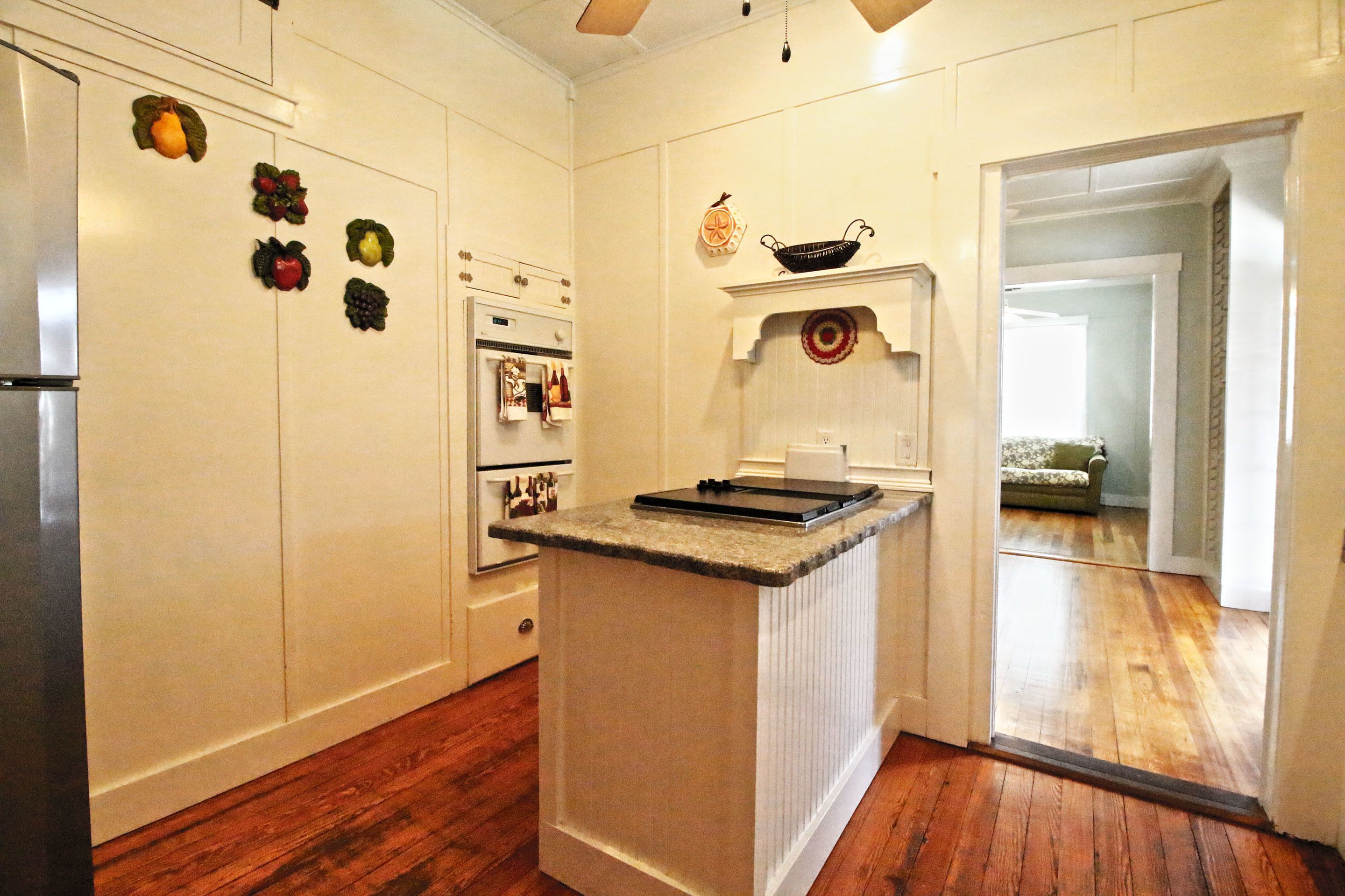 A kitchen with white cabinetry, a central island, and a wooden floor.