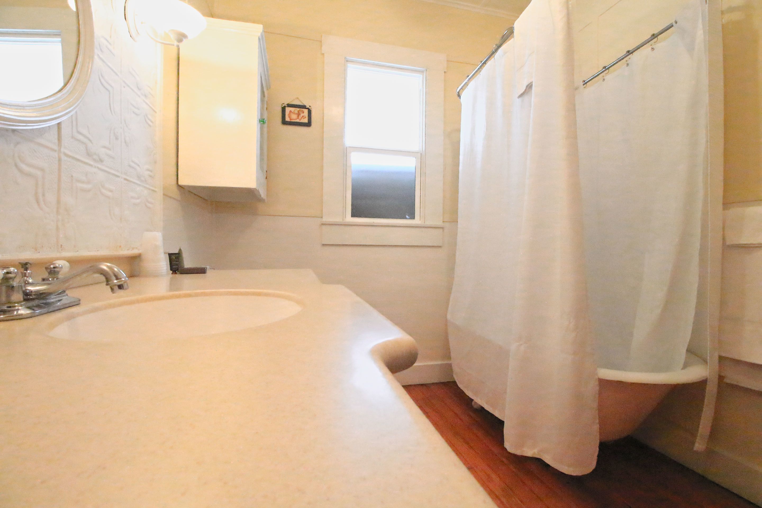 A bathroom with a sink, mirror, window, and shower curtain.