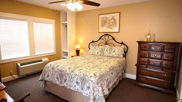 A bedroom with a bed, dresser, and a ceiling fan.