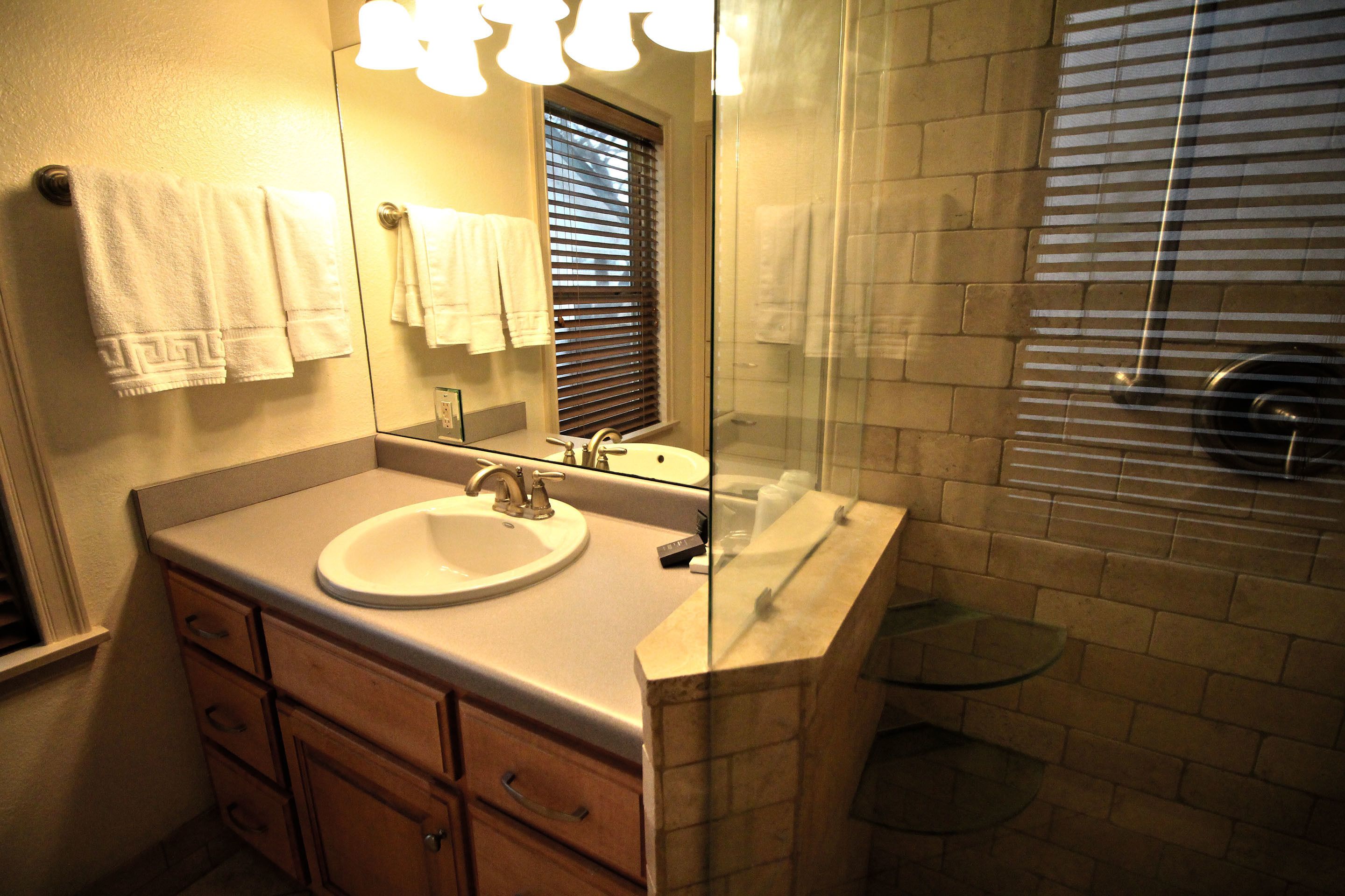 A bathroom with a sink, mirror, and glass shower enclosure.