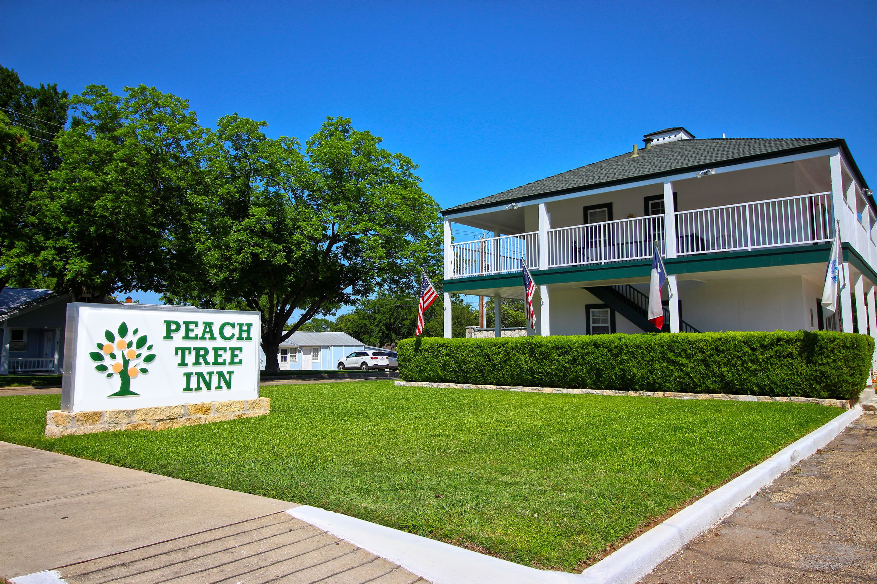 A two-story building with a balcony, a sign reading "Peach Tree Inn," and American flags.