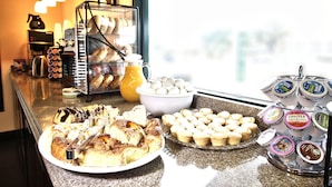 A breakfast buffet with pastries, muffins, and coffee options.