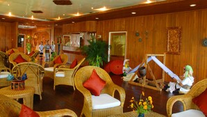 A spacious room with wicker furniture, a massage chair, and a massage table.