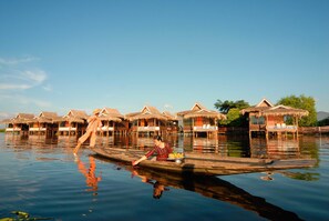 Overwater bungalows with thatched roofs, wooden walkways, and a calm water body. - Paramount Inle Resort (Nyaungshwe)