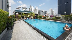 A rooftop swimming pool with a city skyline in the background.