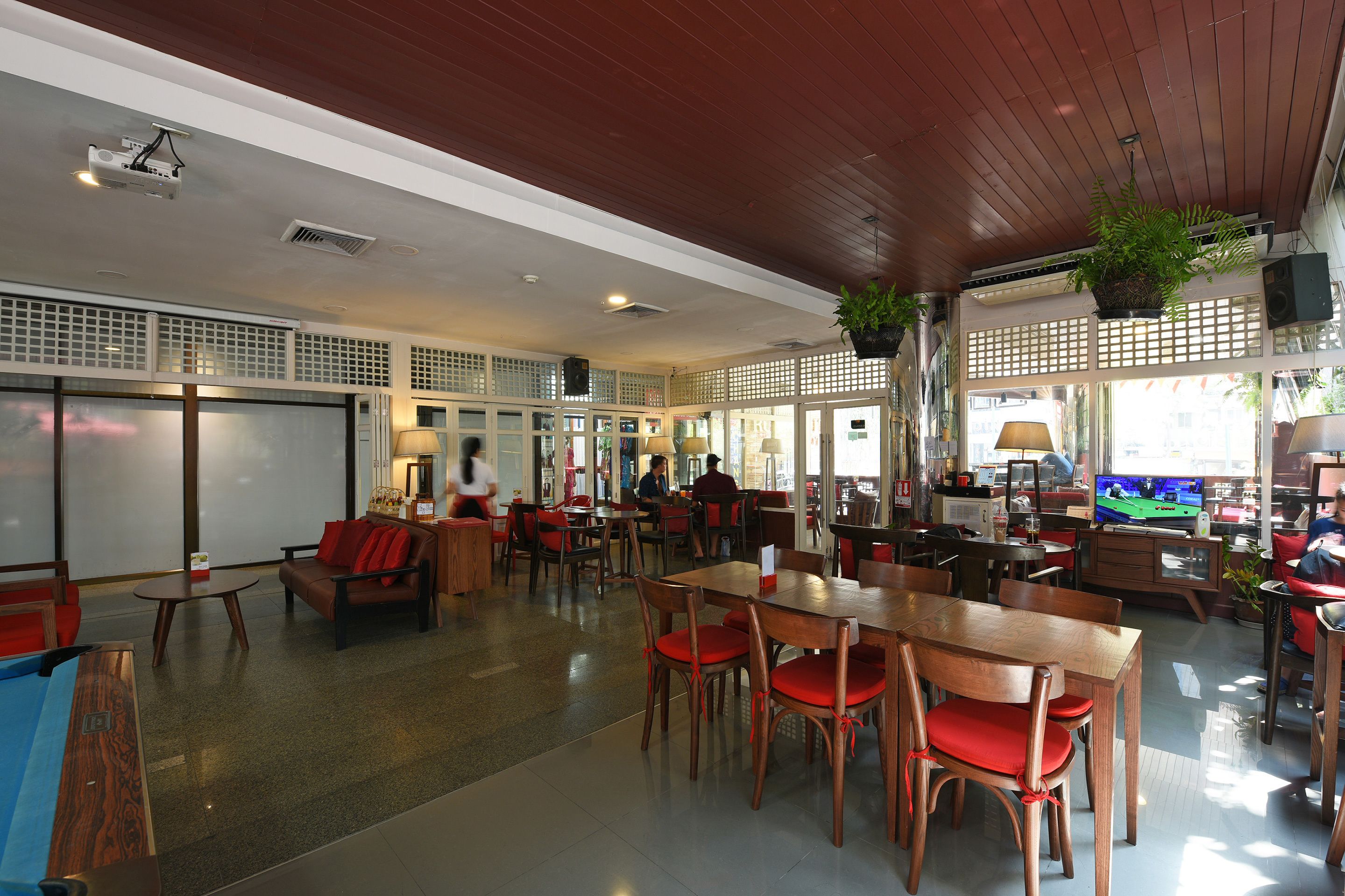 A spacious indoor area with wooden tables and chairs, a pool table, and a television.