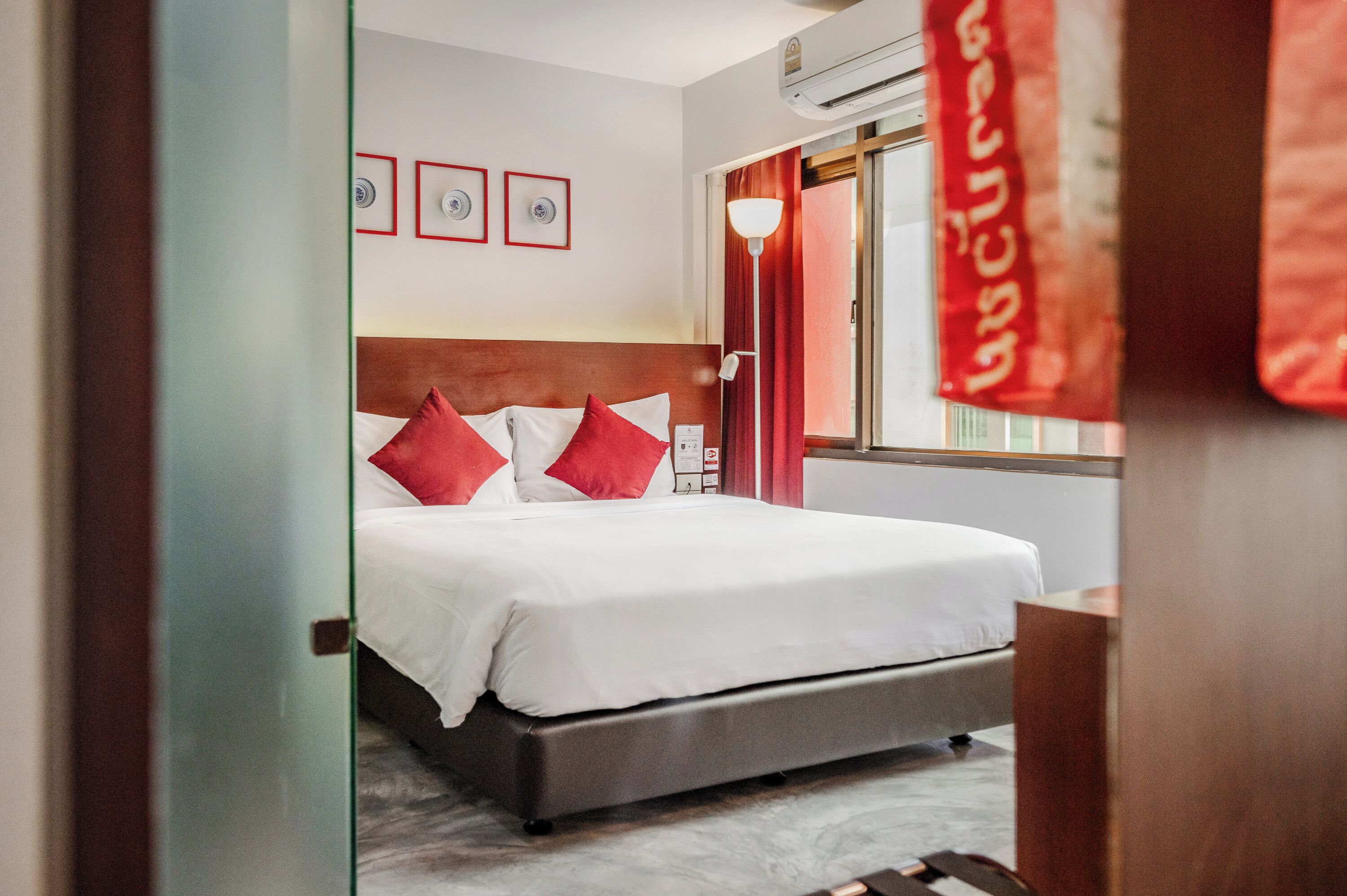 A hotel room with a bed, a nightstand, a lamp, and a window with curtains.
