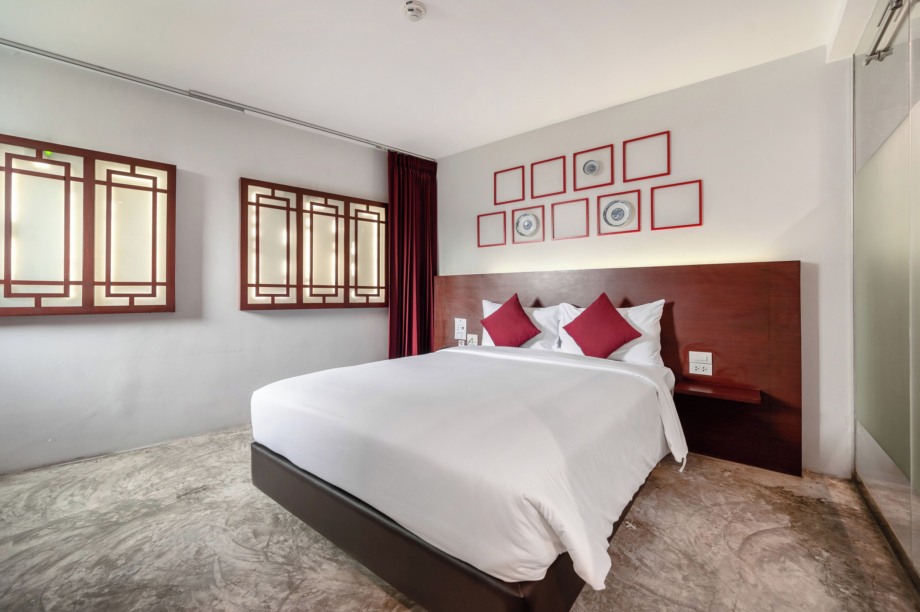Una habitació d'hotel amb un llit gran, un capçal de fusta i una paret amb quadres.