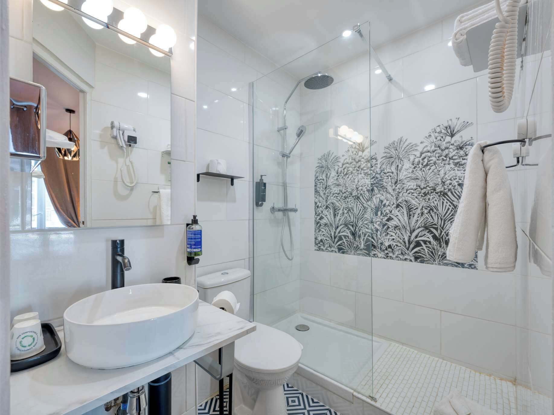 Un baño moderno con ducha envuelta en vidrio, un lavamanos grande y blanco, y un inodoro.