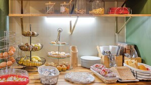 A breakfast buffet with various food items and utensils. - Hotel de Belfort (Paris)