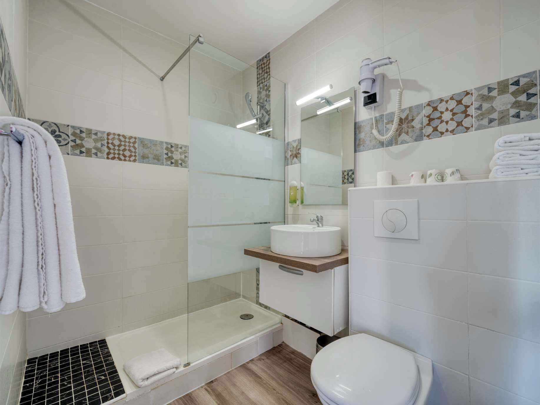 A modern bathroom with a glass-enclosed shower, a white sink, and a toilet.