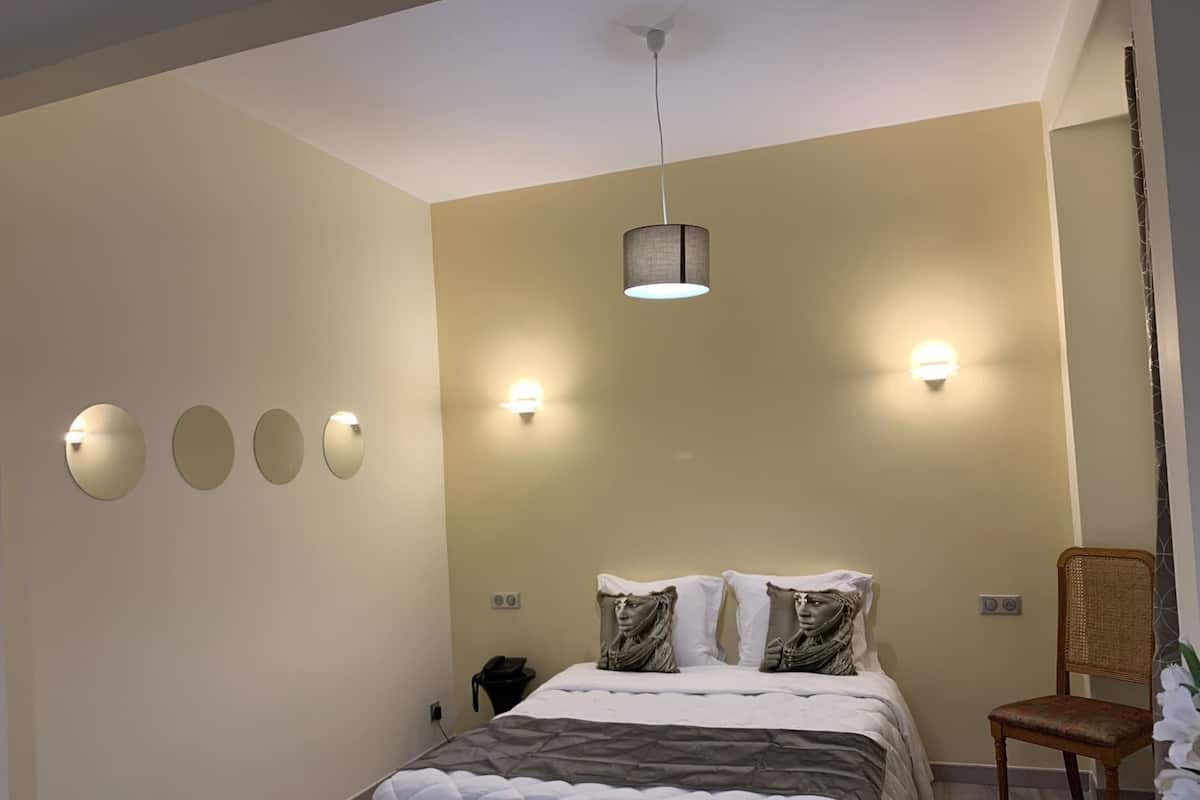 A bedroom with a bed, bedside lamps, a chair, and a ceiling fan.