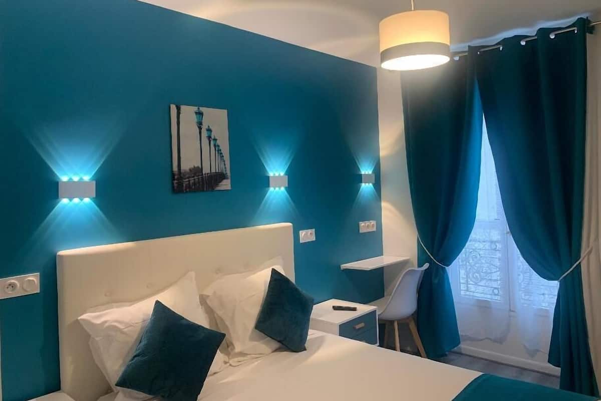 A hotel room with a bed, bedside tables, a desk, and a chair.