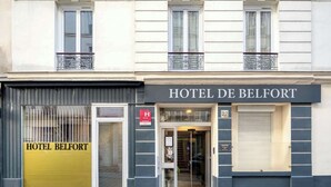 A hotel facade with a prominent entrance, a yellow door, and a sign reading "HOTEL DE BELFORT". - Hotel de Belfort (Paris)