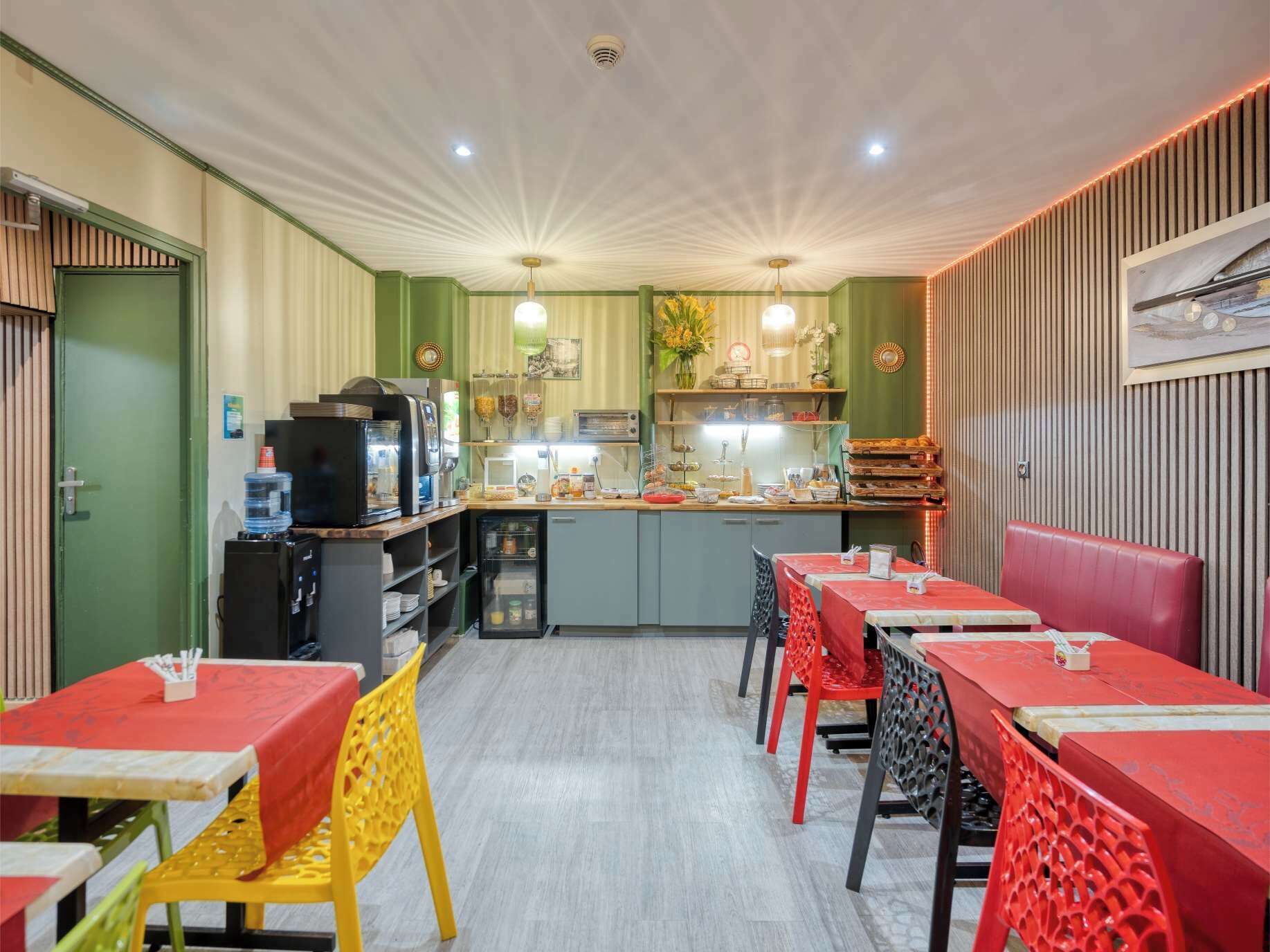 Un restaurant doté d’un espace cuisine, de plusieurs tables avec des chaises rouges et jaunes, et d’une variété de produits alimentaires exposés sur des étagères.