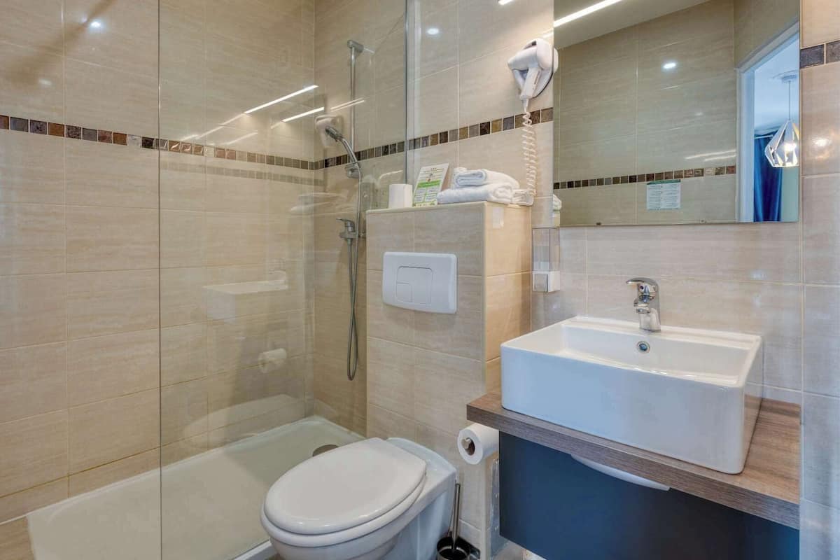 A modern bathroom with a glass shower enclosure, a white toilet, and a sink with a mirror above it.