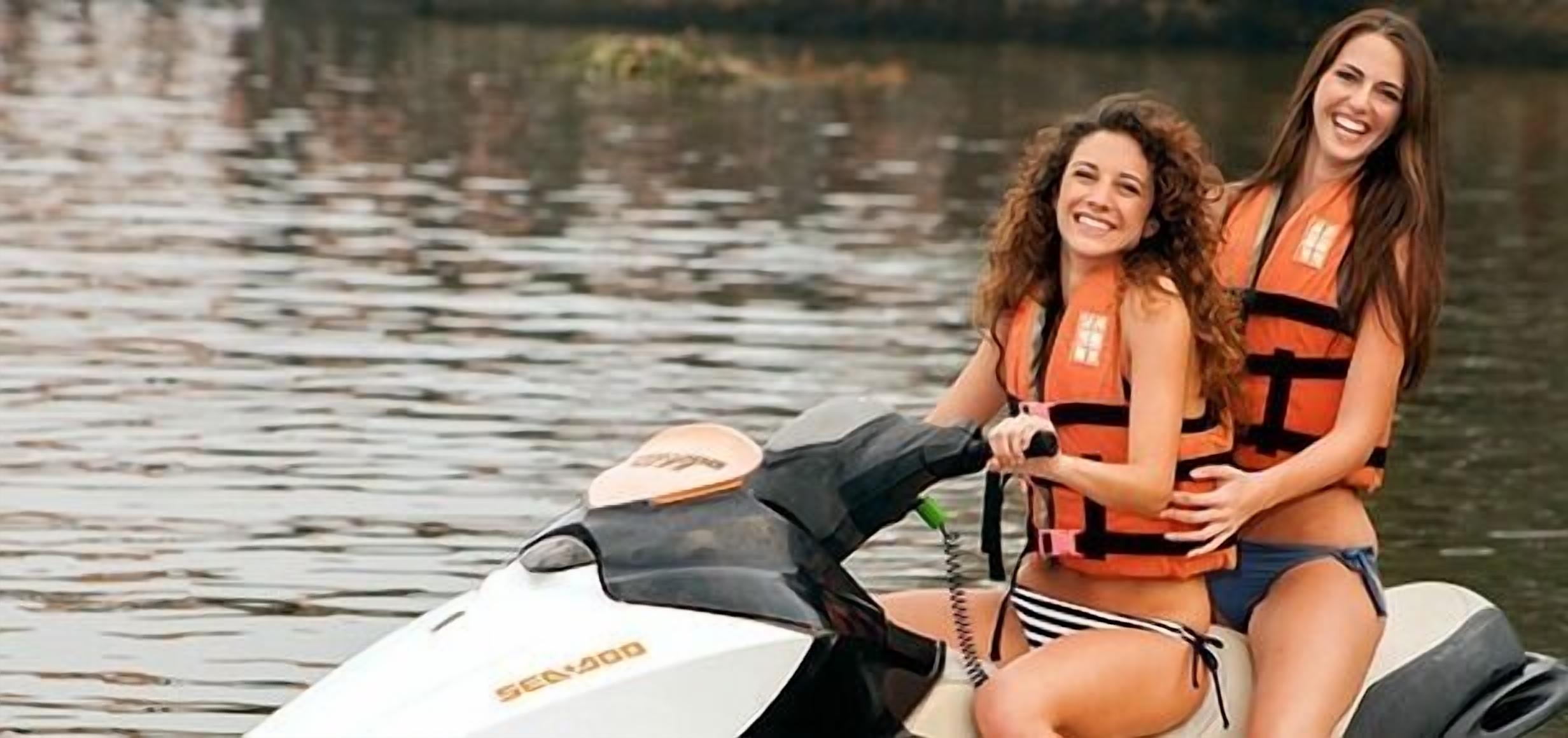 Two people on a Sea-Doo jet ski, wearing life jackets.