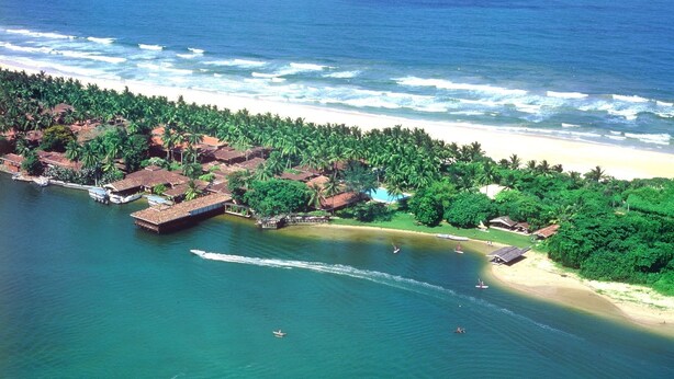 An aerial view of a coastal resort with beachfront villas, a marina, and a beach. - Club Bentota (Bentota)