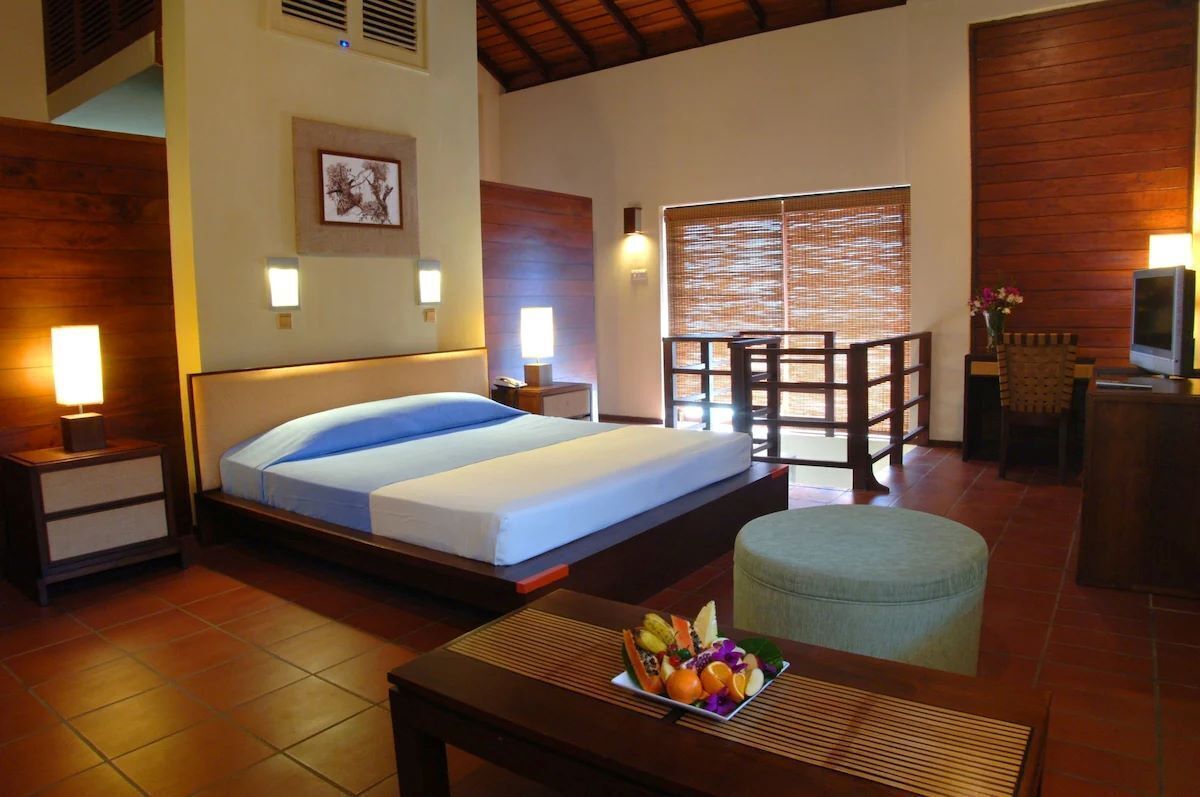 A hotel room with a bed, bedside tables, a desk with a chair, a television, and a window with a view.