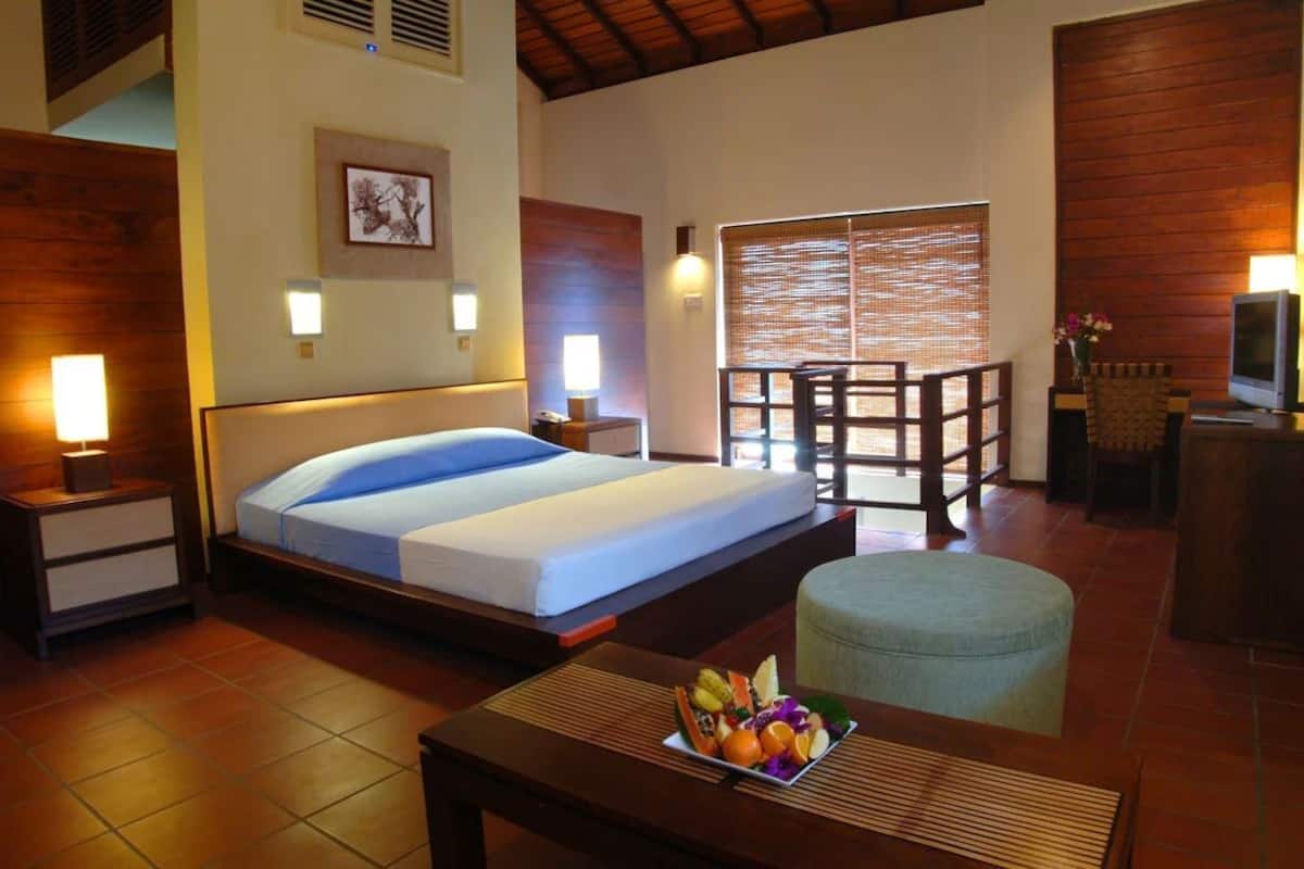 A hotel room with a bed, bedside tables, a desk with a chair, a television, and a window with a view.