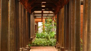 A corridor with wooden pillars and a brick wall, leading to a garden area with plants. - Club Bentota (Bentota)
