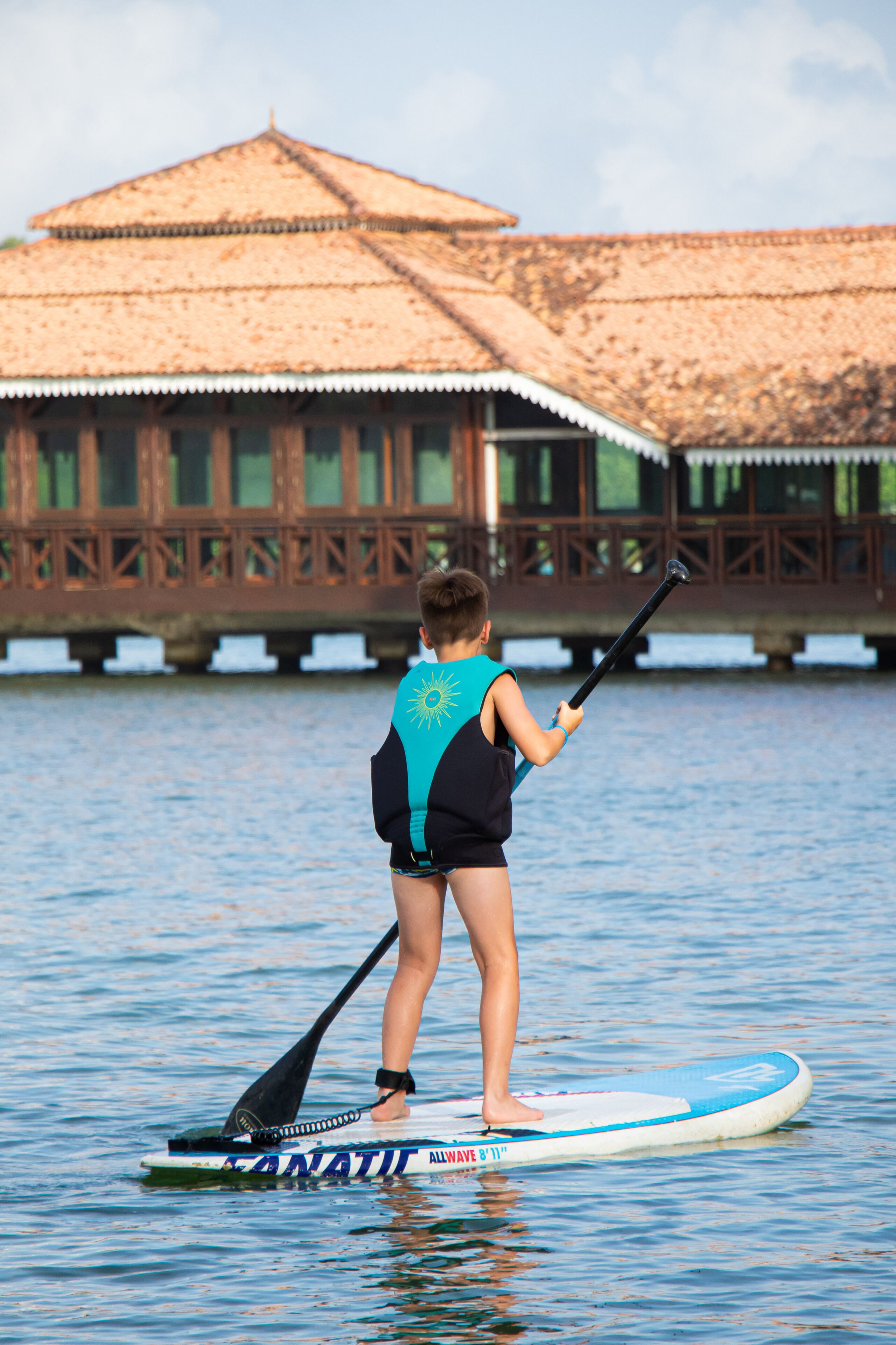 A person paddleboarding on a water body with a traditional building in the background.