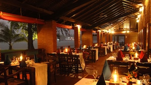 A restaurant with tables set for dining, featuring a view of the water and palm trees. - Club Bentota (Bentota)