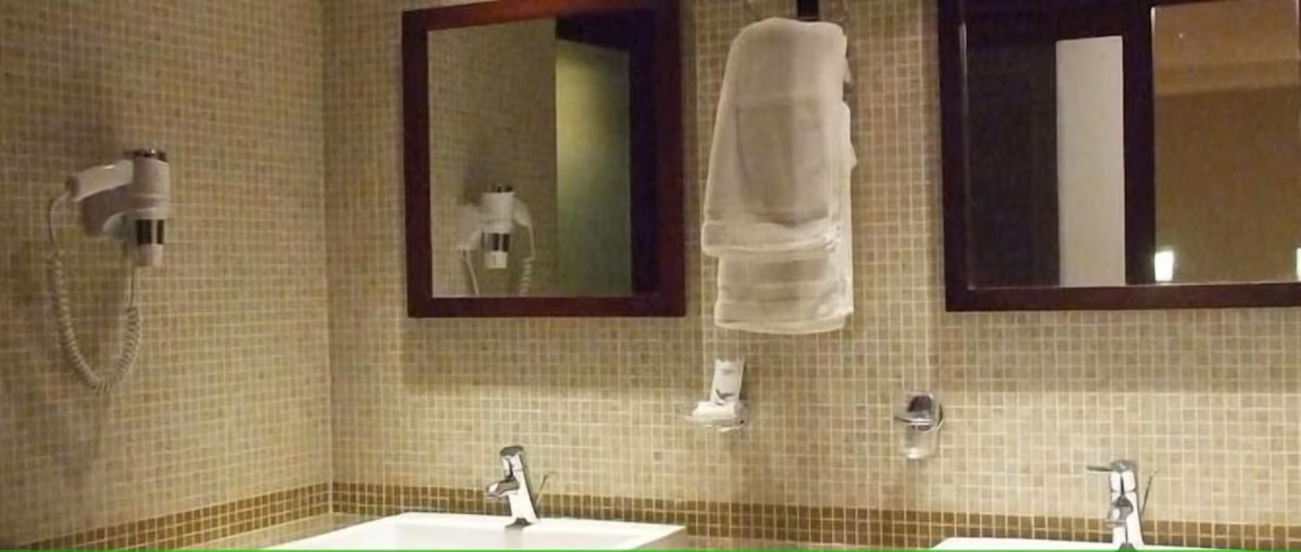 A bathroom with two sinks, a towel rack, and a mirror.