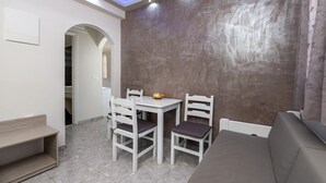 A dining area with a white table and chairs, a bench, and a sofa. - Villa Anemomilos (Santorini)