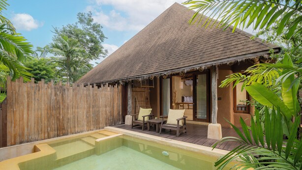 Un área junto a la piscina con terraza de madera, una estructura de techo de paja y una valla de madera.