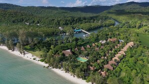An aerial view of a resort with beachfront properties, a dock, and a river.