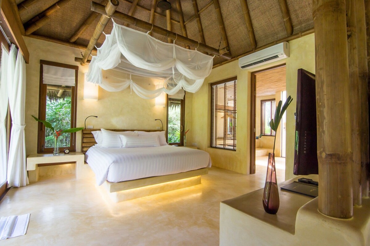 A bedroom with a bed, bedside tables, a nightstand, a bedside lamp, a window, and a door.