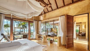 A spacious bedroom with a large bed, a desk with a TV, and a view of the beach and palm trees. - High Season Pool Villa & Spa (Ko Kood)