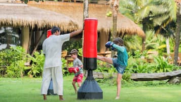 Train in a serene outdoor setting surrounded by lush greenery and a thatched-roof structure.