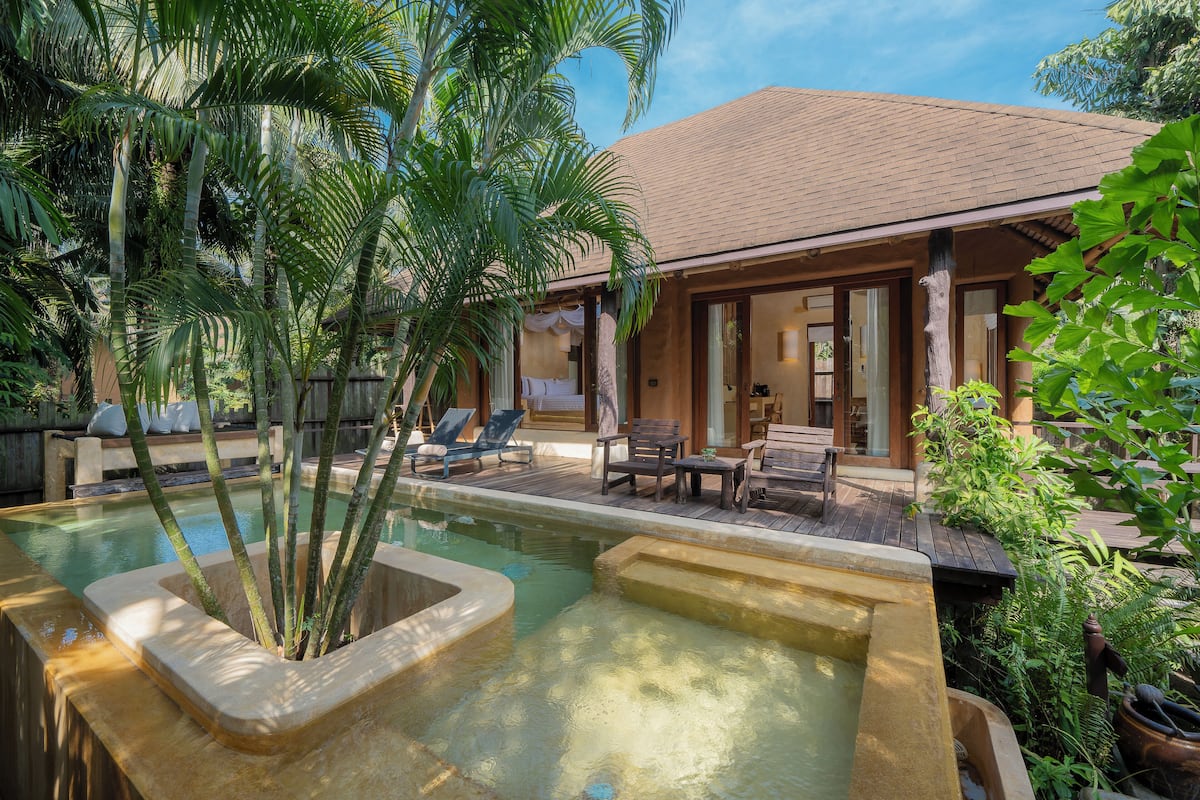 A pool area with lounge chairs, a wooden deck, and a building with large windows.