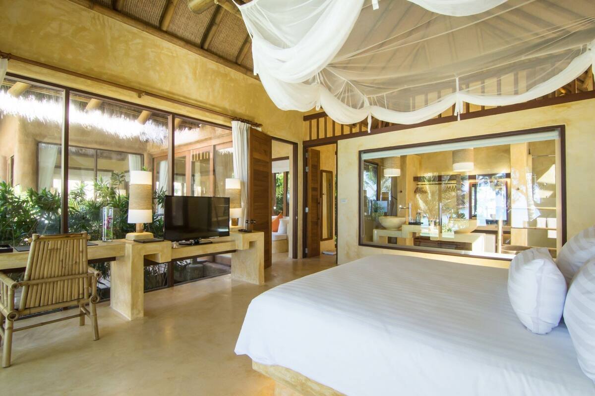 A spacious bedroom with a large bed, a television, and a seating area with a chair and table.