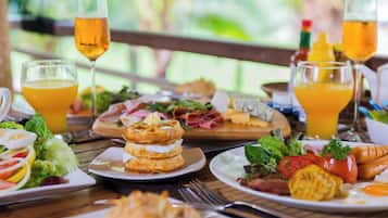 A breakfast buffet with various dishes, drinks, and a wooden table setting.
