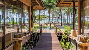 A wooden deck leading to a beach with glass walls and a thatched roof structure. - High Season Pool Villa & Spa (Ko Kood)