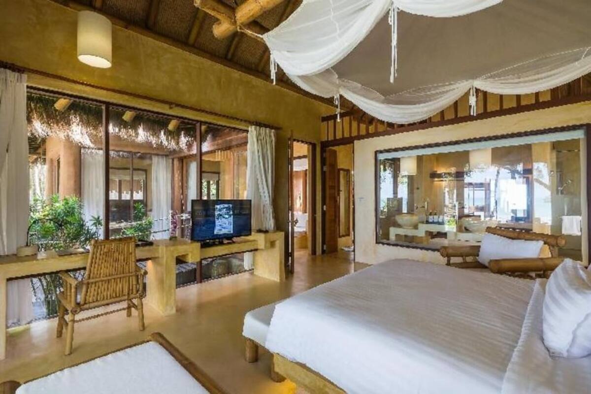 Een kamer met een bed, een televisie, een bureau en een groot raam.