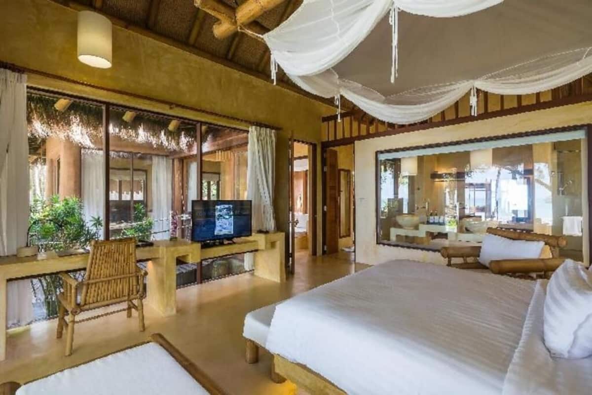 Una habitación con una cama, televisión, escritorio y un ventanal grande.