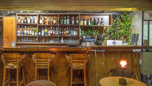 Zona de bar con mobiliario de madera, una variedad de botellas de licor y una pizarra de menú.