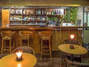 Zona de bar con mobiliario de madera, una variedad de botellas de licor y una pizarra de menú.