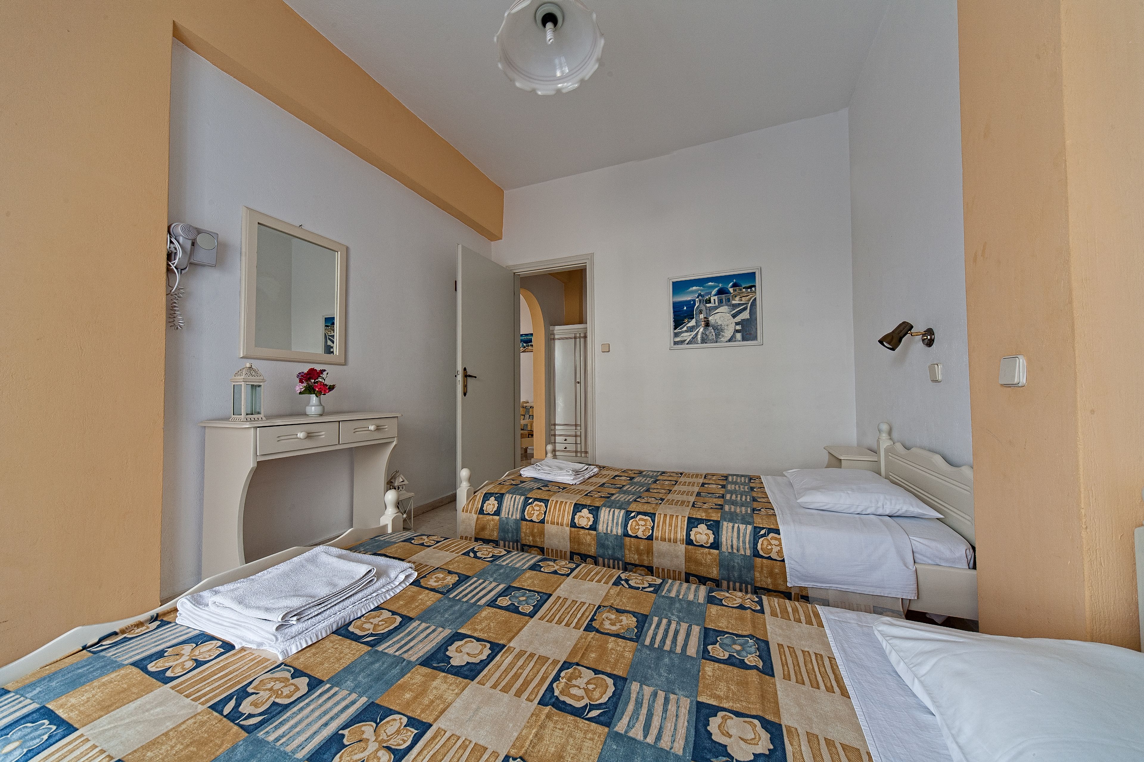 Ein Hotelzimmer mit zwei Betten, einem Schreibtisch, einem Spiegel und einem Gemälde.