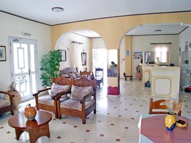 Uma sala de estar ampla com sofás, uma mesa de centro e uma área de jantar com mesa e cadeiras.