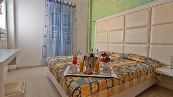 Un dormitorio con una cama, una mesita de noche, un escritorio y una silla. Hay una ventana con cortinas, un aire acondicionado de pared y una pared verde.