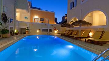 Una piscina al aire libre, sombrillas, sillones reclinables de piscina