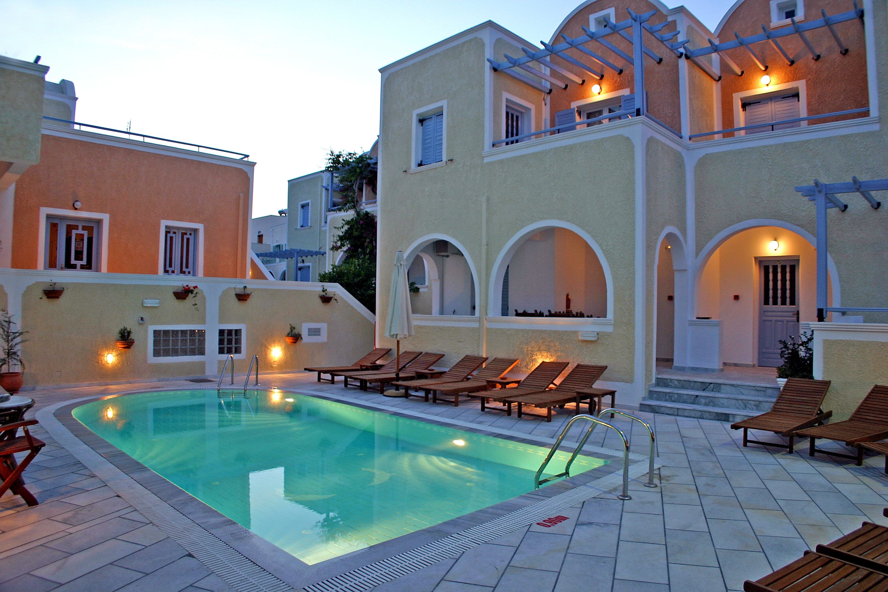 A swimming pool with lounge chairs and a covered area with lights.