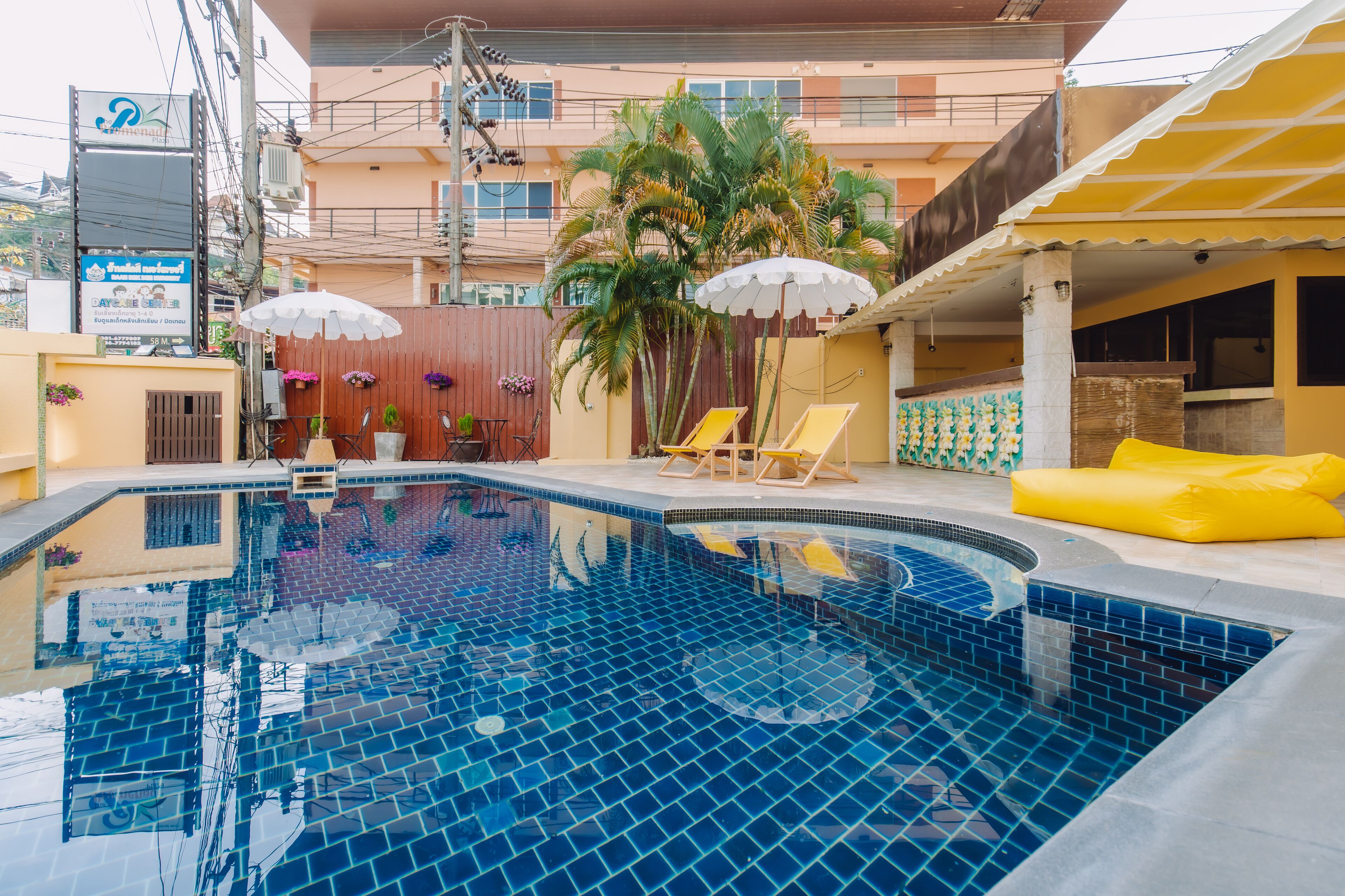 A swimming pool with tiled blue floor, surrounded by lounge chairs and yellow cushions.