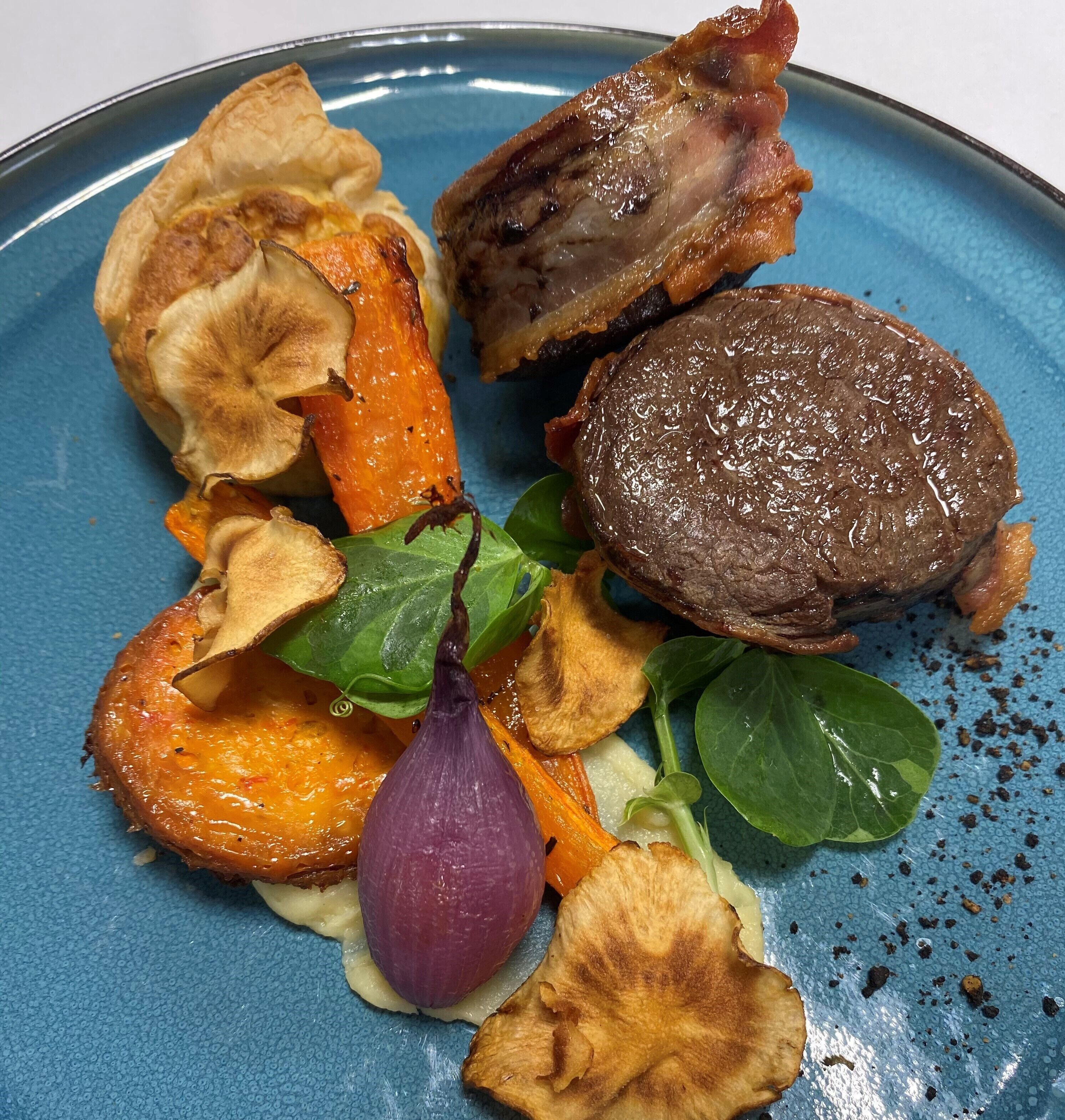Um prato com bife, batatas assadas e cebola vermelha.